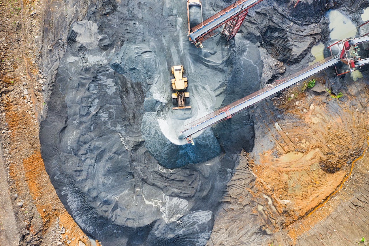 Aerial view of a large industrial mining site with heavy machinery and conveyor belts in operation.